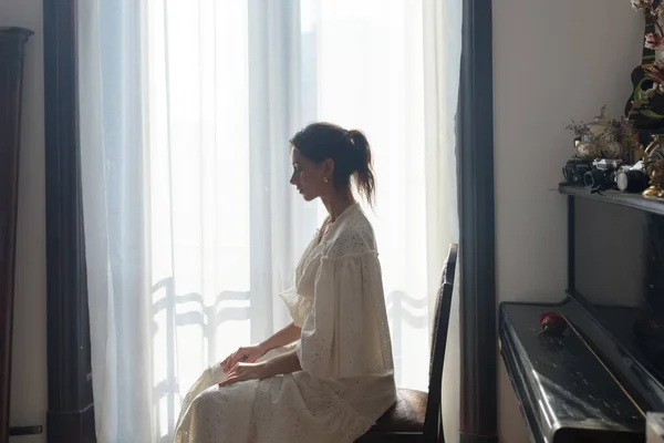 Portrait of a beautiful young woman near the piano.