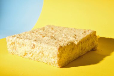 Napoleon cake on a yellow background. Shot from the side. Place for the logo