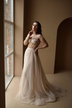 İçerideki odada oturan genç kız pencereye oturur.