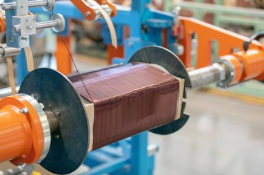Transformatör yapımı. Bobin sarma makinesi çekirdeğin etrafına tel yayıyor.