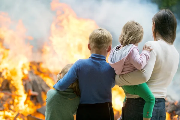 Madre con bambini sullo sfondo della casa in fiamme — Foto Stock