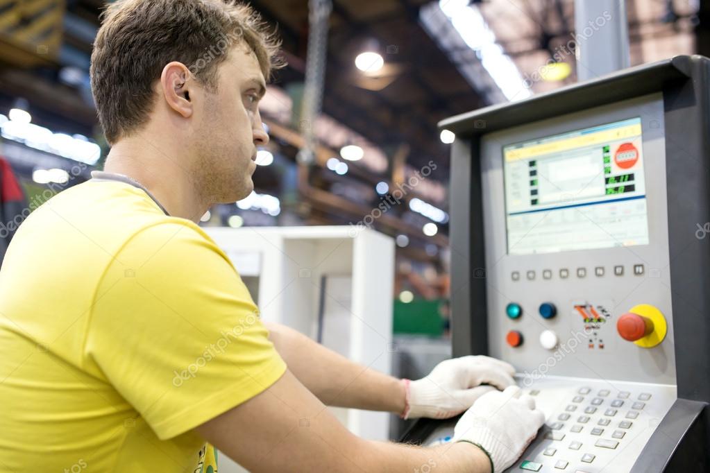 Industrial worker entering data in CNC machine
