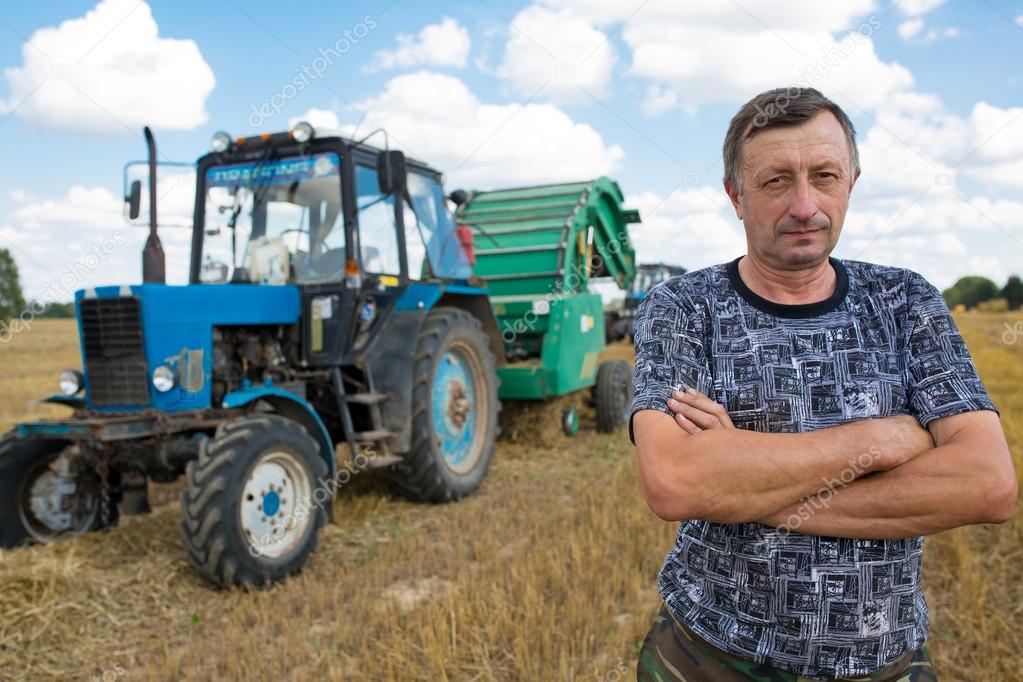 Farmer standing in front of Tractor with Straw Bale Press Machine