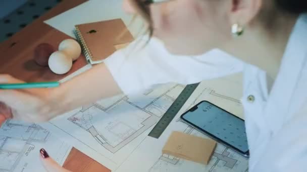 Joven ingeniera bonita, arquitecta o diseñadora trabaja con dibujos en la oficina — Vídeos de Stock