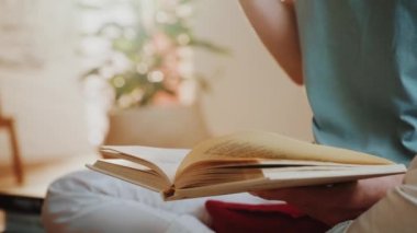 Elinde bir fincan çay ya da kahve tutan ve kitap okuyan bir kadın..