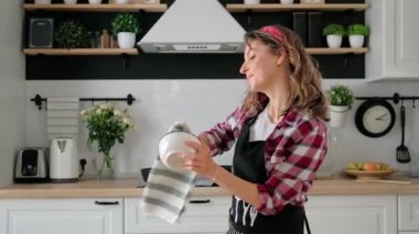 Dertsiz, mutlu, genç kadın ev hanımı tek başına yemek pişiriyor.