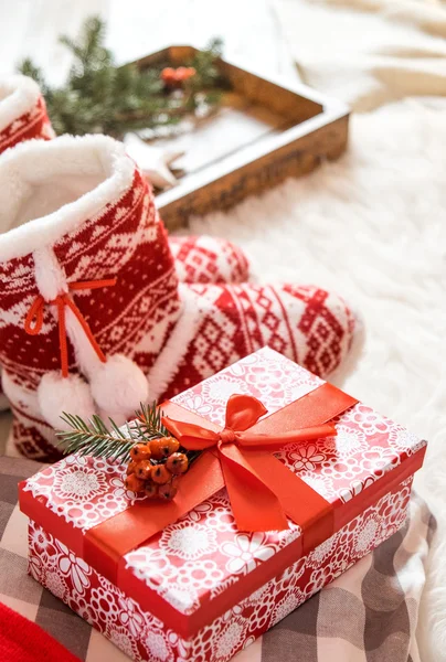 Gift box and christmas slippers on the floor in bright house. — Stok fotoğraf