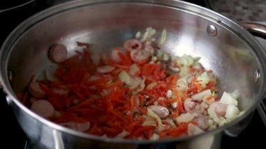 Soğan, havuç ve sosis kızartma tavasında kızartılır.