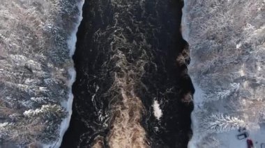 Kışın karlı ormandaki kara nehrin yukarısında