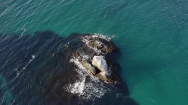 Martılar denizin üzerinde uçar, hava manzarası, dalgalar kayaları yıkar.