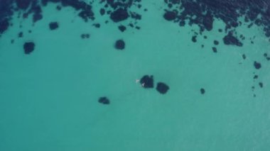 İki kişi temiz mavi su ve resiflerle denizde yüzüyor, yukarıdan aşağıya doğru.