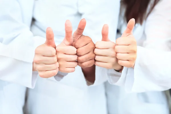 Porträt eines selbstbewussten Ärzteteams, das Daumen hoch zeigt, während es in der Klinik in einer Reihe steht — Stockfoto