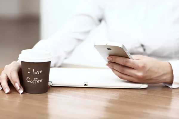 Nahaufnahme einer Frau, die ihr Handy vor die Kaffeetasse hält — Stockfoto