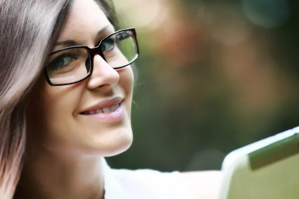 Hermosa joven sonriendo con gafas. Trabajando en portátil . — Foto de Stock