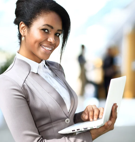 Sorridente mulher de negócios africana com computador portátil — Fotografia de Stock
