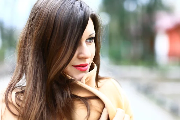 Beautiful young woman in coat in city park Stock Photo