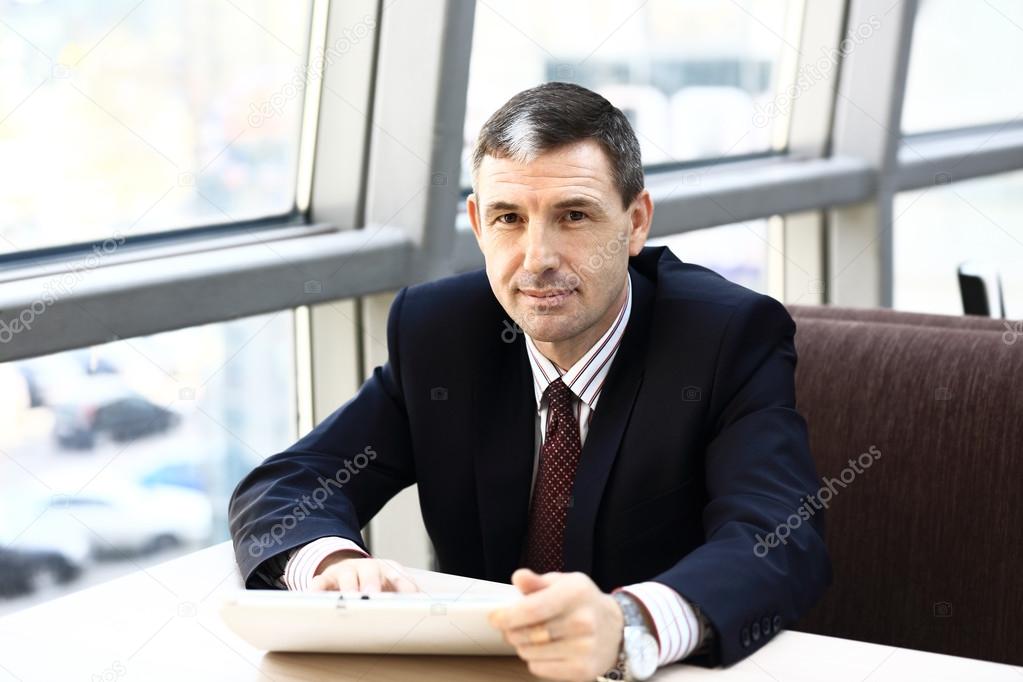 Happy businessman at workplace looking at camera in office