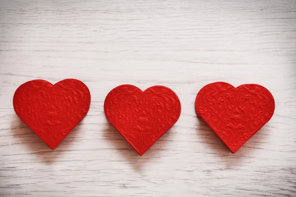 Fondo de San Valentín con tres corazones sobre fondo de madera — Foto de Stock