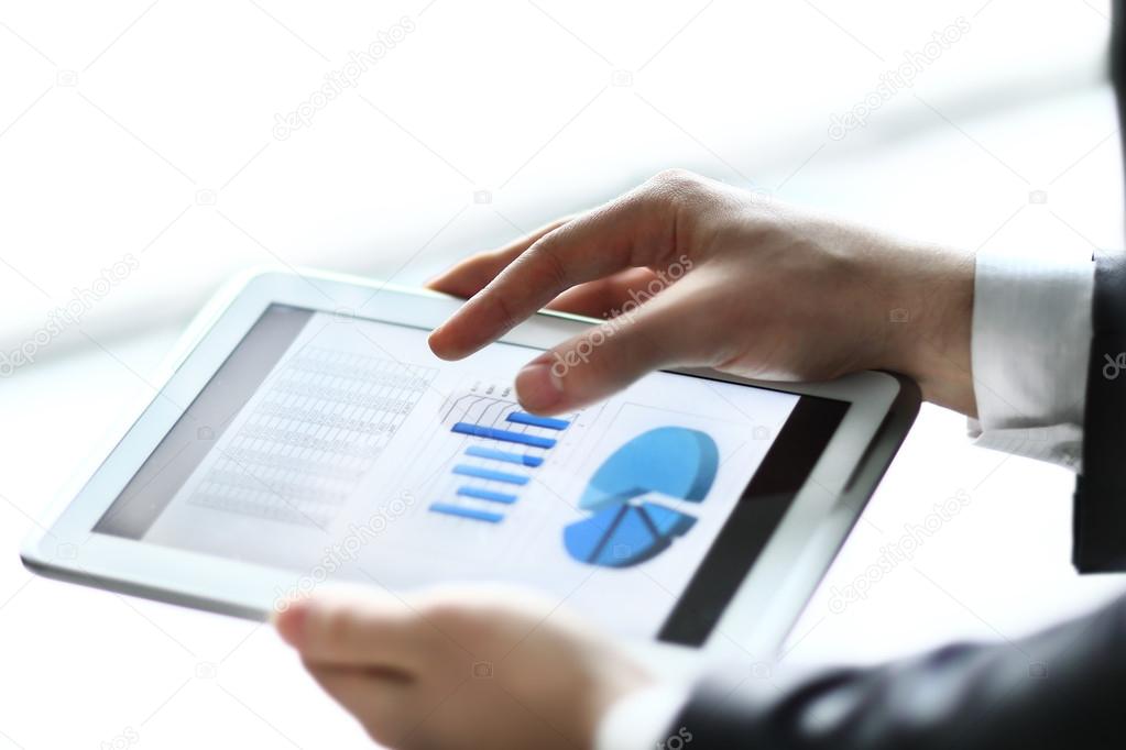 Modern people doing business, graphs and charts being demonstrated on the screen of a touch-pad