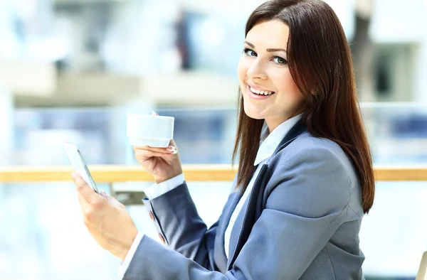 Primer plano de la mujer sosteniendo el teléfono móvil en frente de la taza de café —  Fotos de Stock