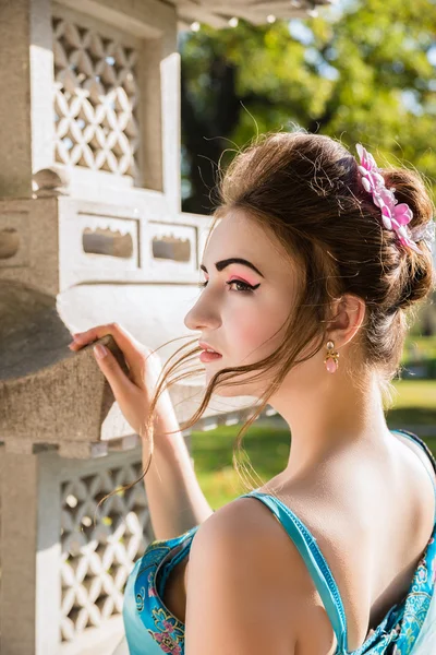 Prachtige geisha in blauwe jurk in de buurt van stenen pagode — Stockfoto