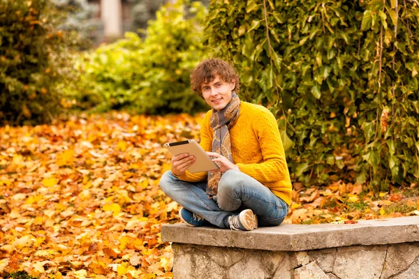 Jonge man met tablet buiten in de herfst — Stockfoto