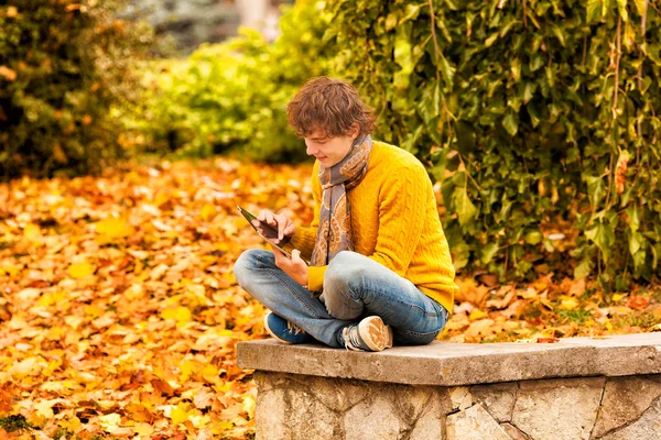Curly man in blue jacket with computer tablet in autumn — Stock Photo, Image