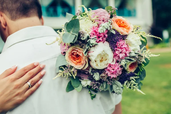 Bride hug groom with wedding bouquet — Stock Photo, Image