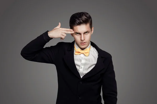 Portrait of young trendy groom with yellow bow-tie with gun sign — Stock Photo, Image