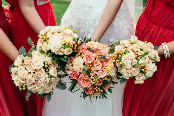 Noiva em vestido de noiva e damas de honra vestir vermelho segurando Wedd — Fotografia de Stock