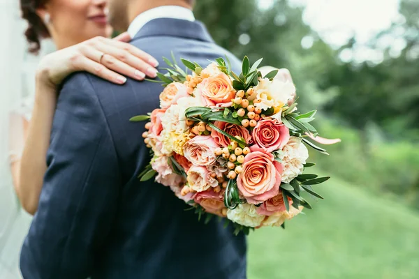 Noiva segurando buquê de casamento e noivo abraço na cerimônia de casamento — Fotografia de Stock