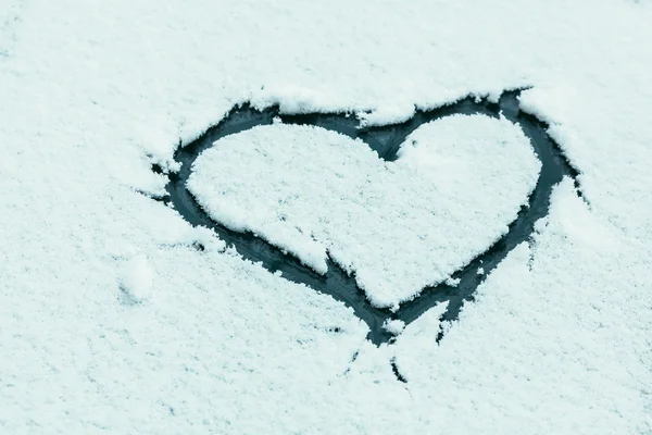 Heart shape on snowy car glass with frash winter snow — Stock Photo, Image