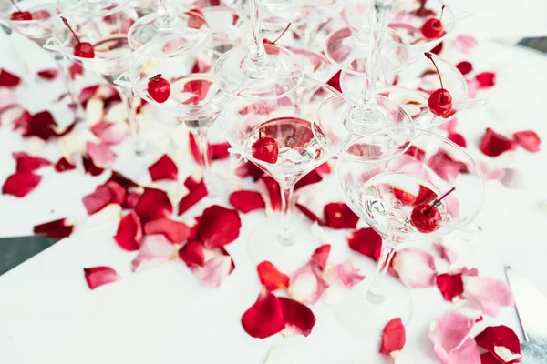 Linie von Kirschchampagner-Cocktails über weißen mit roten Rosen Haustier — Stockfoto