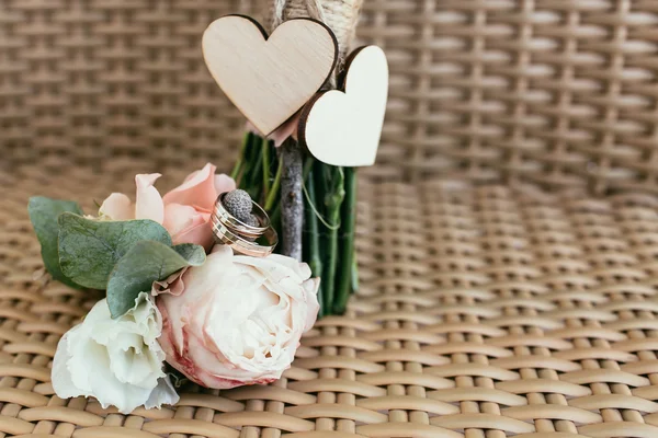 Anillos de boda con rosas rosadas contra dos corazones de madera —  Fotos de Stock