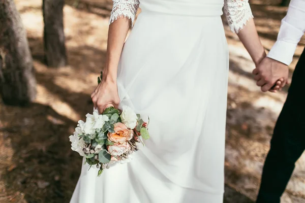 Bruidegom bezit is van een bruid hand met weding boeket op trouwdag — Stockfoto