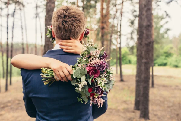 Bruden kram brudgummen med lila rosor bukett på bröllop i — Stockfoto