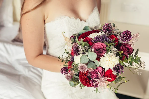 Nevěsta v bílých svatebních šatech drží Lila svatební kytice v on — Stock fotografie