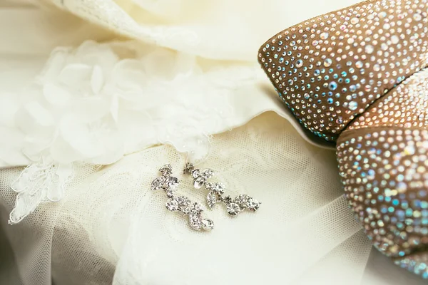Mariées boucles d'oreilles sur fond de robe de mariée — Photo
