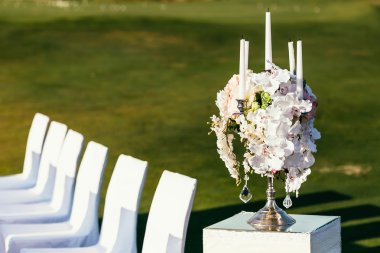 güneşli düğün dekorasyon beyaz sandalye ile tören yerinde-çiçek ve mum