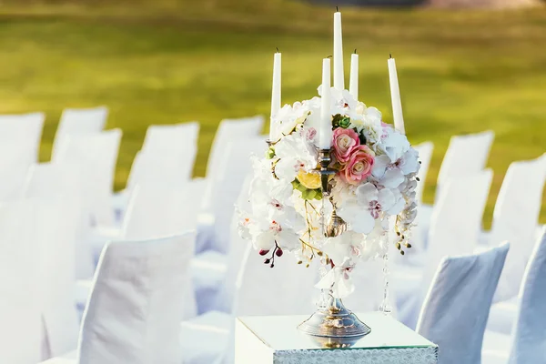 Decoración de la boda con flores y vela en el día soleado en el lugar de la ceremonia con sillas blancas —  Fotos de Stock