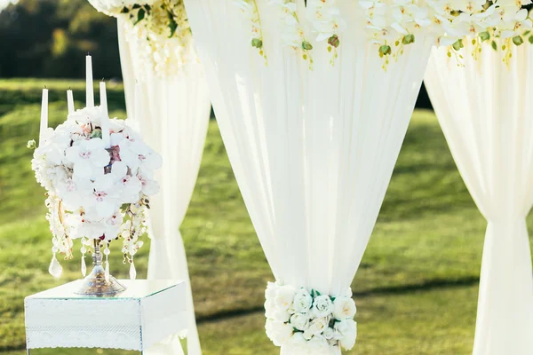 Bröllop arch med blommor och ljus dekoration på solig dag i ceremonin plats — Stockfoto