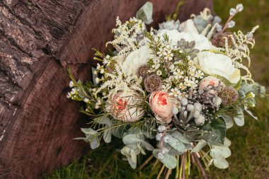 rustic wedding bouquet with roses and succulents on green grass 