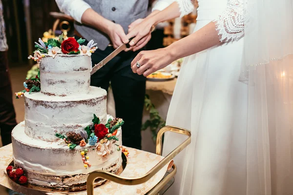 Sposa e sposo taglio torta di nozze rustico sul banchetto di nozze con — Foto Stock