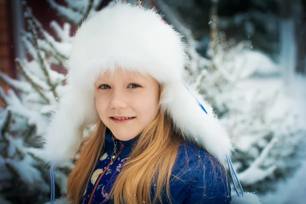 Little girl in a fur hat enjoys winter and snow — Stock Photo, Image