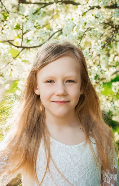 Bambina vestita di bianco su un giardino soleggiato primaverile — Foto Stock