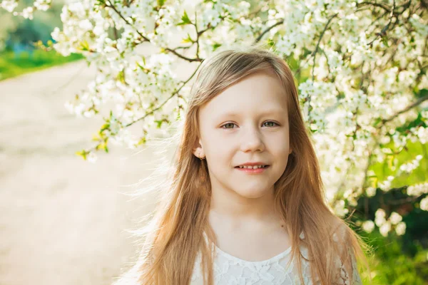 Bambina vestita di bianco su un giardino soleggiato primaverile — Foto Stock