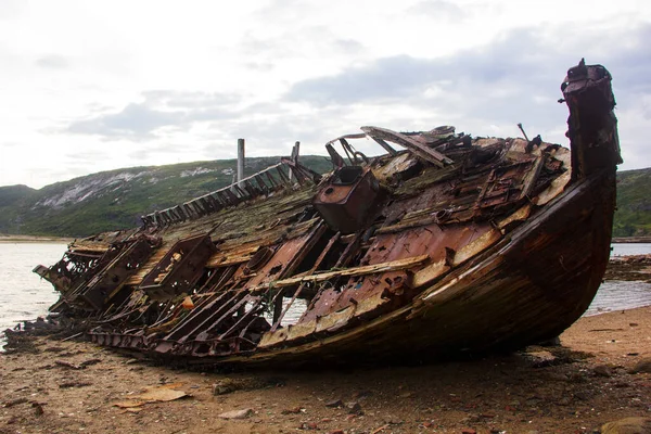 Ship graveyard. A sunken rusty abandoned fishing vessel in Russia, the Kola Peninsula, the Barents Sea, Teriberka.