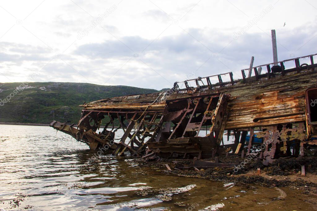 Ship graveyard. A sunken rusty abandoned fishing vessel in Russia, the Kola Peninsula, the Barents Sea, Teriberka.