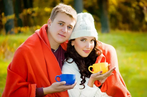 Young couple sitting embracing nature and drinking tea — Stock Photo, Image