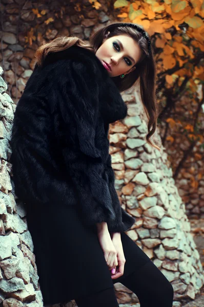 Fashionable young woman posing near a stone wall — Stock Photo, Image